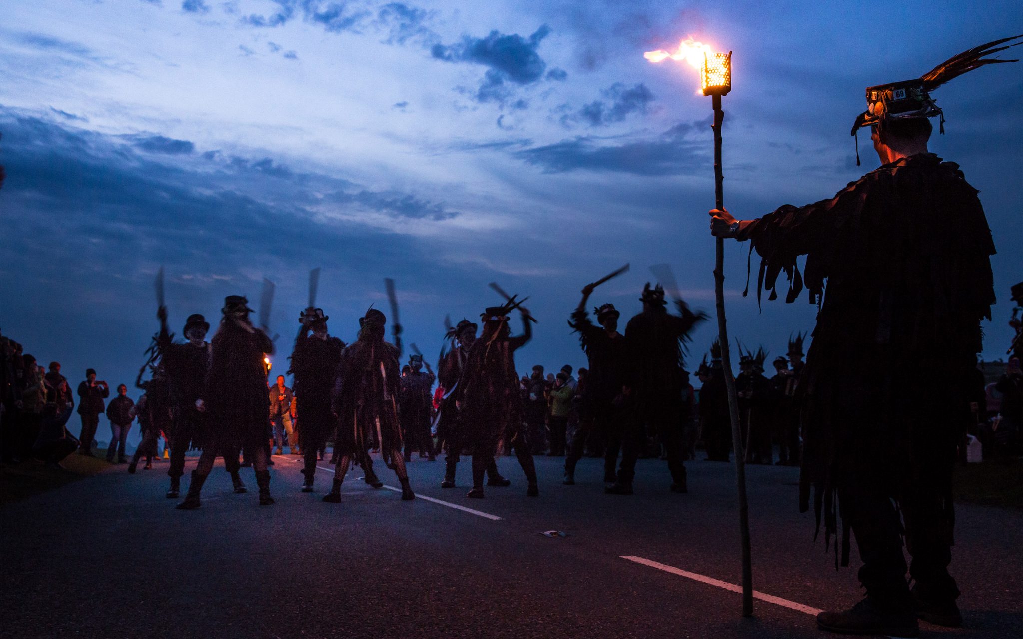 Photo journalism.Morris Dancing at dawn, HayTor on Dartmoor. Based upon ancient Pagan Festival celebrating the coming of summer on May 1st.Early-risers join the revelry with four separate Morris troops at HayTor, on top of Dartmoor. This photograph is ‘Beltane Border Morris Dancers’.The blackened faces is a tradition of the Border Morris folk, as a form of disguise to escape persecution of the law.